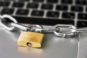 Locked padlock with a metallic chain on a laptop keyboard. photo