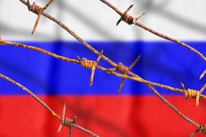 bandera rusa detrás de alambres de púas oxidados con sombras