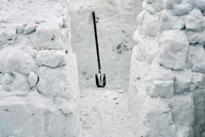 Building of a snow house igloo from snow bricks using a spade photo