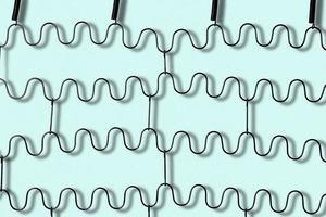 Metal zig zag springs of a folding bed isolated on light blue background photo