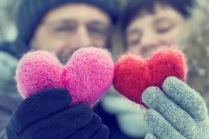 Middle-aged couple holding in hands two woolen hearts outdoors photo