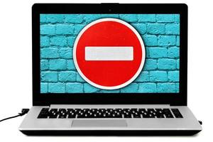 Laptop with the DO NOT ENTER road sign and a blue brick wall on the screen photo