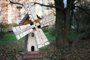 modelo de un antiguo molino de viento de madera en un parque infantil con casa al fondo foto