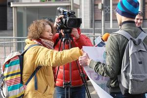 Moscow, Russia - March 10, 2019. Female TV reporter interviewing a young demonstrator holding a political banner photo