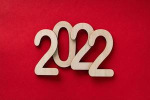 Números de madera del año 2022 sobre el fondo de papel rojo con sombras foto