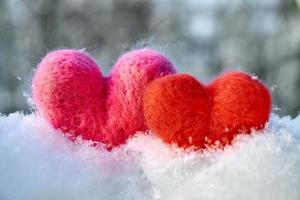 Two wool red and pink hearts standing on the white fluffy snow photo