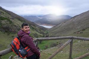 mujer excursionista con mochila sonriendo en un mirador de montaña foto