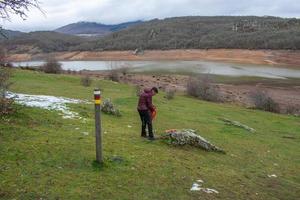 woman hiker with backpack next to a mountain lake photo