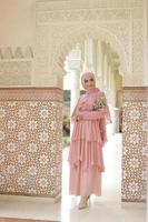 Full body portrait of lady use a wedding dress, wedding makeup on hijab. Malay or indonesia wedding dress, beauty or eidul fitri concept. Beautiful southeast asian muslim woman posing at the mosque photo
