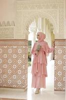 retrato de cuerpo completo de dama usa un vestido de novia, maquillaje de boda en hijab. vestido de novia malayo o indonesia, concepto de belleza o eidul fitri. hermosa mujer musulmana del sudeste asiático posando en la mezquita