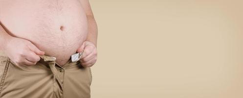 hombre corpulento con sobrepeso con vientre gordo incapaz de cerrar los pantalones - concepto de obesidad y adiposidad foto
