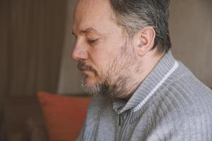 middle-aged man alone at home and looking down and depressed photo