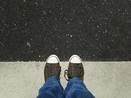 pies en zapatos de lona sobre asfalto alineados con marcas viales foto
