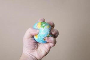 hand crushing globe of planet earth - ecocide or destruction of environment concept photo