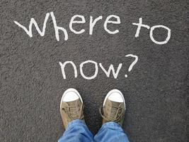 feet standing on road with where to now question written on asphalt photo