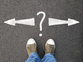 feet standing on asphalt with arrows pointing left and right with question mark photo