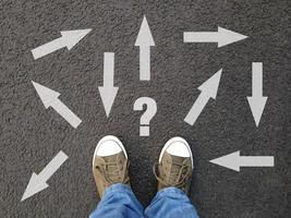 feet standing on asphalt with multitude of arrows in diffrent directions photo