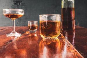 Liquor  glass and liquor bottles on wooden table photo