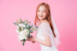 Young Asian bride posing on pink background photo