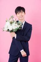 Young Asian groom posing on pink background photo