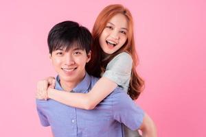 Young Asian couple posing on pink background photo