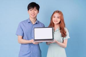 Young Asian couple using laptop on blue background photo