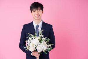 Young Asian groom posing on pink background photo
