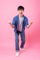 Young Asian man posing on pink background photo