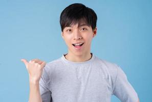 Young Asian man posing on blue background photo