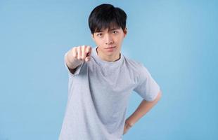 Young Asian man posing on blue background photo