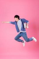 joven asiático saltando sobre fondo azul foto
