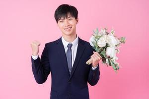 Young Asian groom posing on pink background photo