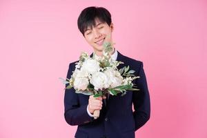 Young Asian groom posing on pink background photo