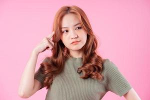 Young Asian woman posing on pink background photo