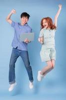 Young Asian couple using laptop on blue background photo