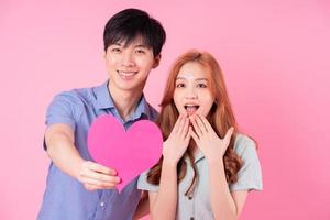 Young Asian couple posing on pink background photo