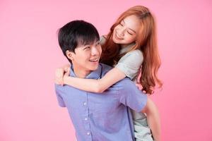 Young Asian couple posing on pink background photo