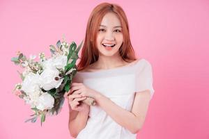 Young Asian bride posing on pink background photo