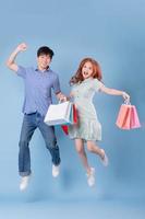 Young Asian couple carrying shopping bag on blue background photo