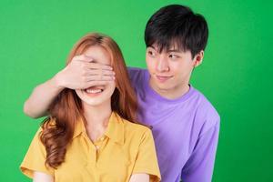 Young Asian couple posing on green background photo