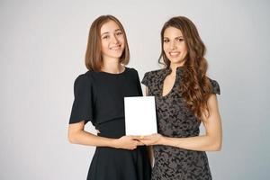 dos mujeres jóvenes felices sosteniendo una maqueta en el fondo foto
