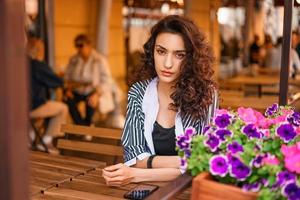 portrait of a beautiful girl sitting at a table in a cafe on the street photo