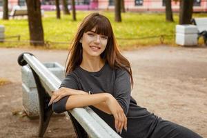 cute young woman smiling in the Park on a wooden bench photo