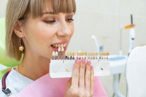 happy woman in dentistry picks up the color of tooth enamel photo