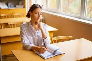 cute student sitting with a notebook at the Desk by the window, thoughtful view photo