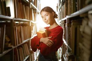 The girl holds a book in her hands against the background of the library. photo