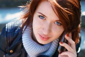 Redhead girl talking on the phone. Close-up portrait, beautiful eyes photo