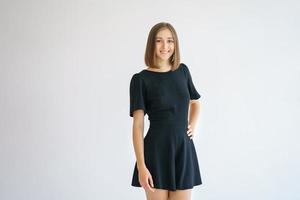 Portrait of a happy cute woman in a black dress on a white background smiling photo