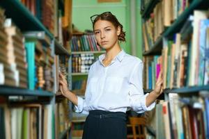 A nice woman in a white shirt in the library is smiling photo