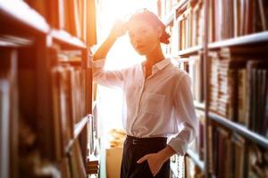 student stands between the rows in the library, photo